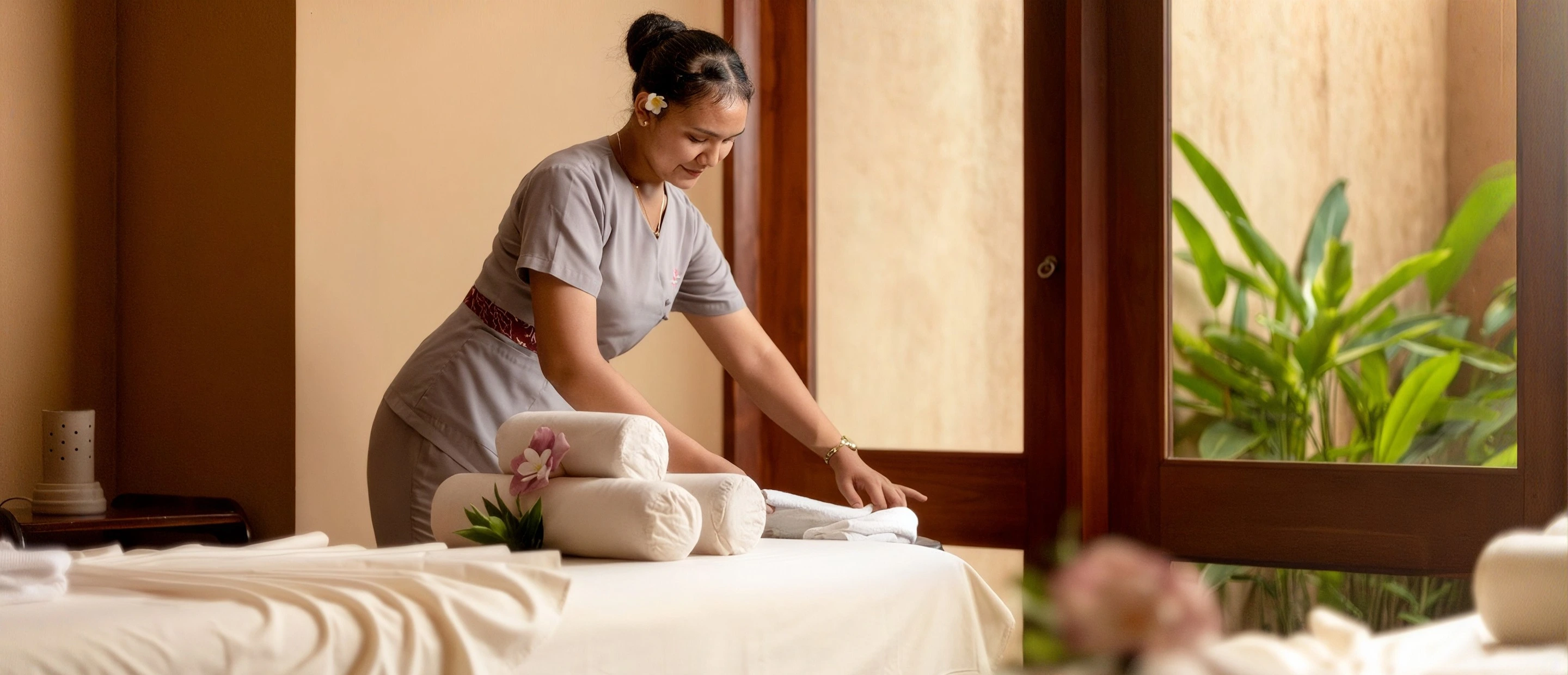 A spa therapist preparing a treatment bed